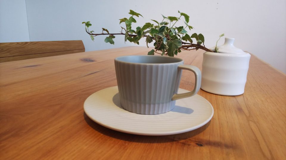 グレーのカップ＆ソーサーが植物と一緒に飾られている様子。